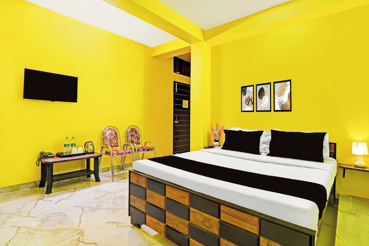 A hotel room with a bed, a TV, a desk with a telephone, and chairs.