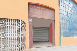 A building entrance with a metal gate, a roll-up door, and a window with a grid pattern.