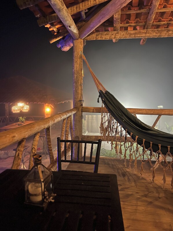 A hammock suspended from a wooden structure with a view of a night scene.