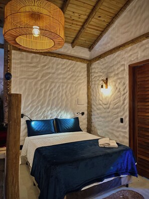 A bedroom with a bed, a textured wall, a wooden ceiling, and a hanging light fixture.