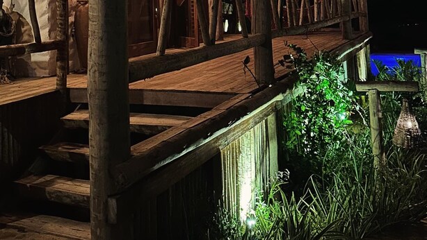Un edificio rustico in legno con un balcone, ringhiere in legno e lampade a sospensione.
