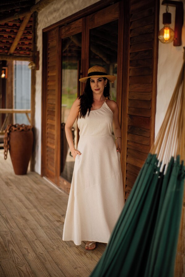 A person standing in a wooden room with a large potted plant and a hammock.