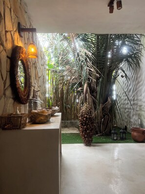 A room with a stone wall, a hanging light fixture, a woven basket, and a potted plant.