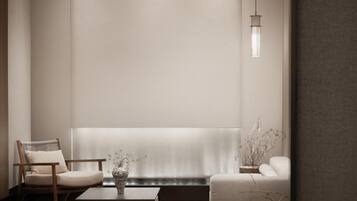 Un salón minimalista con sofá, sillón, mesa de centro y un jarrón con ramas.