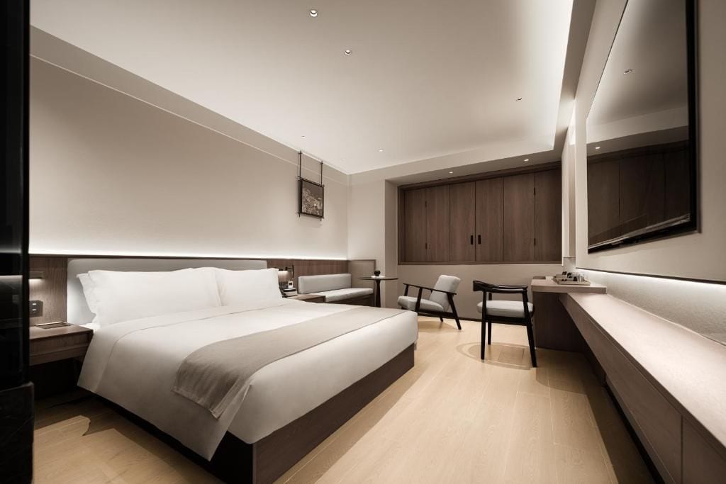 Una habitación de hotel moderna con una cama grande, un escritorio, una silla y un sofá.
