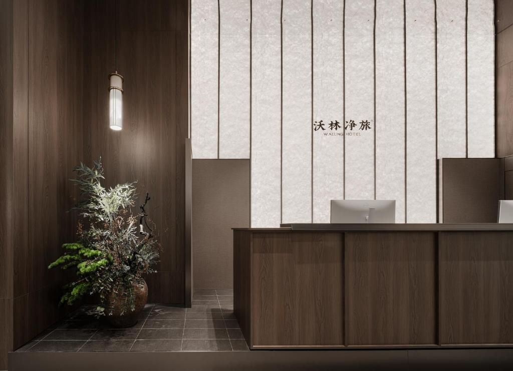 A reception desk with a wooden finish and a potted plant beside it.