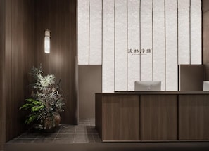 A reception desk with a wooden finish and a potted plant beside it.