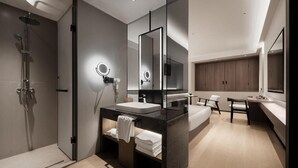 Een moderne badkamer met een douche, een wastafel, een spiegel en een badkamerkast.