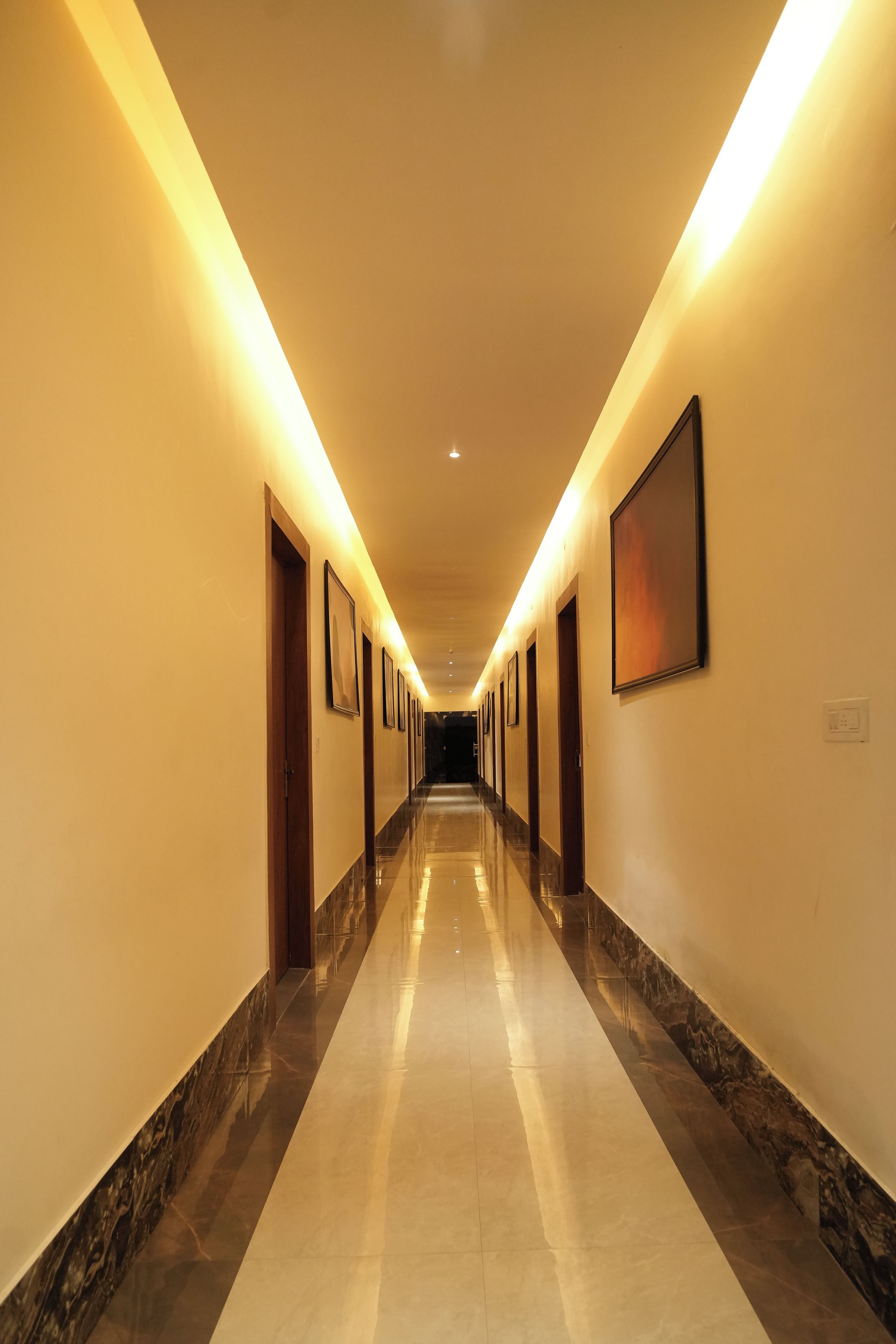 Un pasillo largo y bien iluminado con puertas a ambos lados que dan a habitaciones.