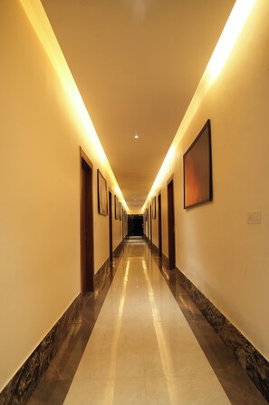 A long, well-lit hallway with doors on both sides leading to rooms.