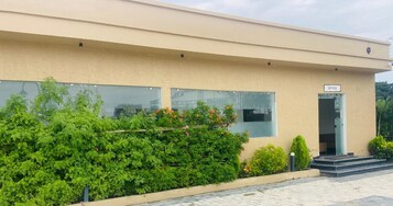 A modern building with a beige facade, a glass entrance, and a sign labeled 'OFFICE'.