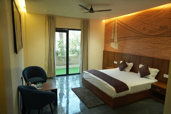 A hotel room with a bed, a desk, a chair, a view of the outdoors, and a ceiling fan.
