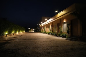 A paved pathway leading to a building with multiple windows and a well-lit entrance. - The Kailasha Resort (Roorkee)