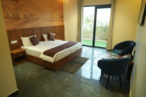 A bedroom with a large bed, a nightstand, a chair, and a view of the outdoors.
