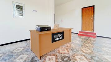 A reception desk with a sign indicating it's company-serviced, a fire extinguisher, and a wooden door in the background.