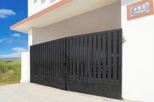 A gated entrance to a building with a clear sky and vegetation in the background.