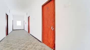 Un pasillo con piso estampado, puertas de madera y un extintor en la pared.