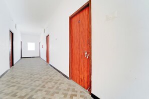 A corridor with a patterned floor, wooden doors, and a fire extinguisher on the wall.