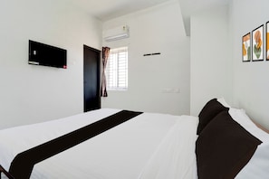 A hotel room with a bed, a flat-screen TV, an air conditioning unit, a window with curtains, and a wall-mounted power outlet. - Hotel O Neelambur Near PSG ITech (Sulur)
