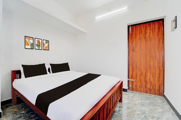 Une chambre d’hôtel avec un lit, une porte en bois et trois œuvres d’art encadrées accrochées au mur.