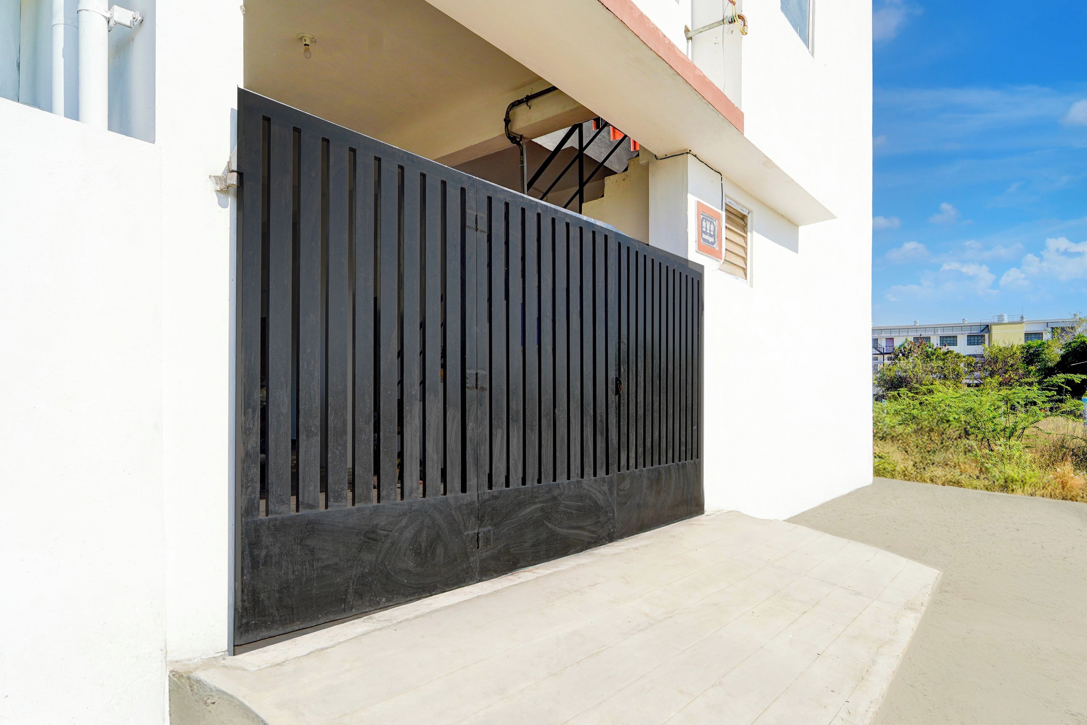 Un edificio moderno con una reja metálica negra, una escalera de hormigón y un cielo despejado.