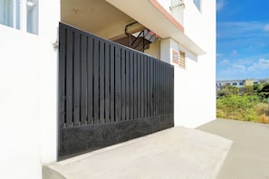 A modern building with a black metal gate, a concrete staircase, and a clear sky. - Hotel O Neelambur Near PSG ITech (Sulur)