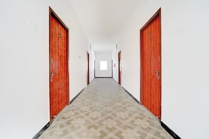 Um corredor com portas de madeira, piso estampado e uma janela no final.