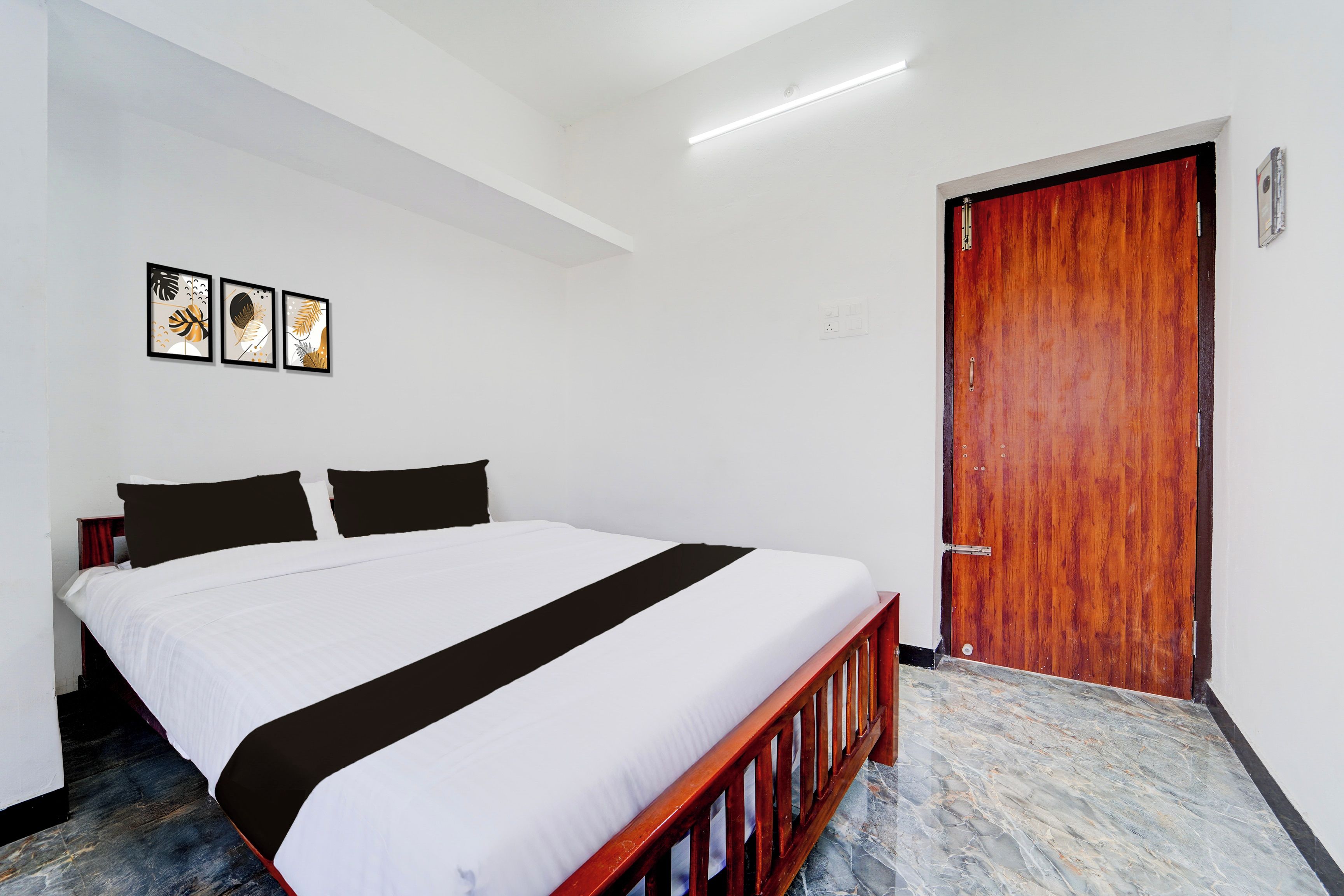 Una habitación de hotel con cama, una puerta de madera y una lámpara en el techo.