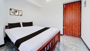 Hotellihuone, jossa on sänky, puuovi ja kattovalaisin.