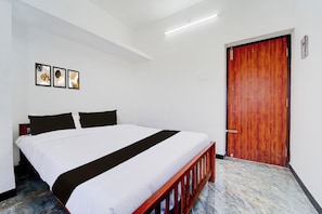 Quarto de hotel com cama, porta de madeira e luminária no teto.