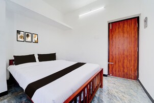 A hotel room with a bed, a wooden door, and a ceiling light.