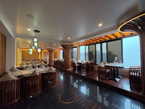 A restaurant with a modern interior, large windows, and a view of the sea.
