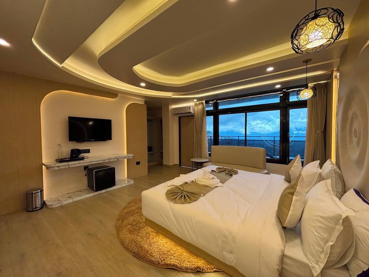Habitación de hotel moderna con una cama grande, un televisor de pantalla plana, un minibar y vistas al exterior.