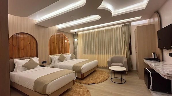 A modern hotel room with two beds, a desk, a chair, and a TV.
