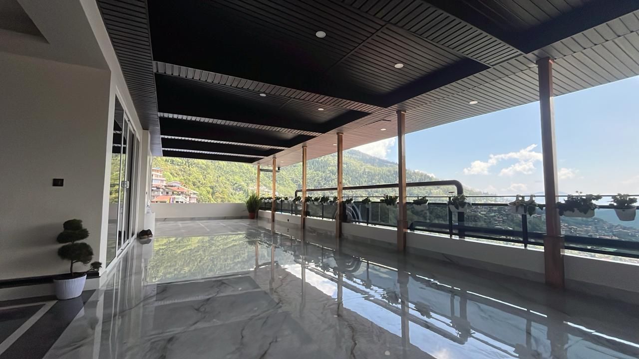 A spacious balcony with a reflective floor, large windows, and a view of a mountainous landscape.