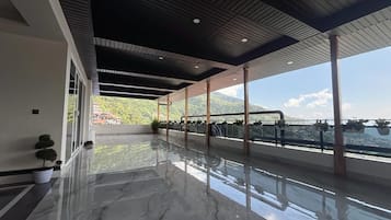 A spacious balcony with a reflective floor, large windows, and a view of a mountainous landscape.