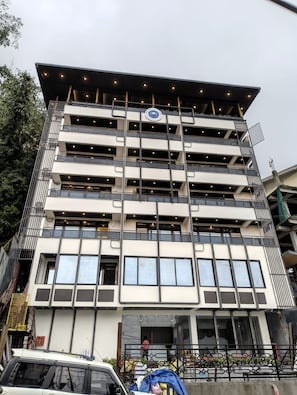 A multi-story building with a modern architectural design, featuring a series of balconies and large windows.