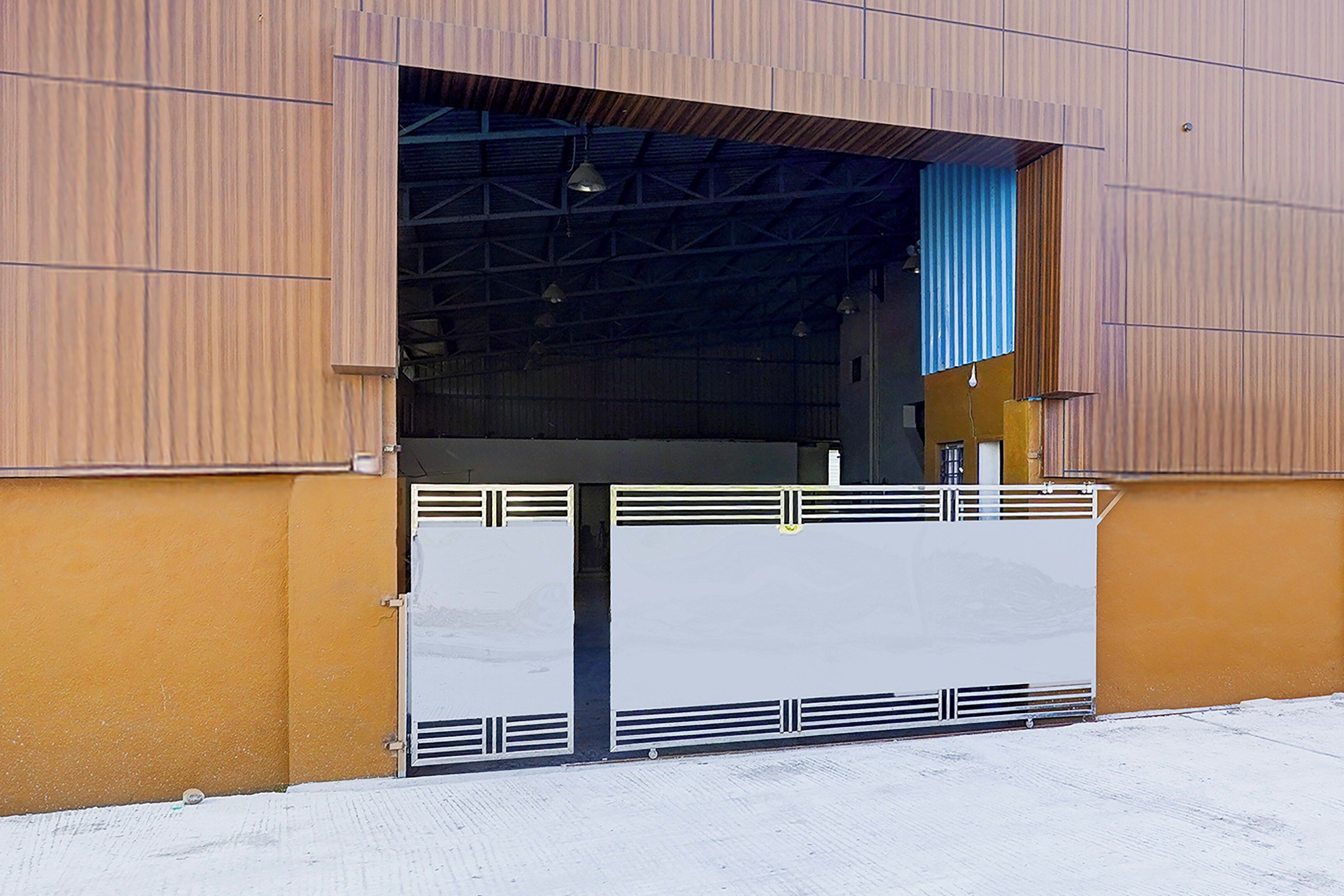 Un grand bâtiment industriel à la façade métallique et doté d’une large porte d’entrée ouverte.
