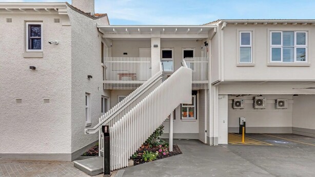 A residential building with a central staircase, a garage, and a parking area. - Pilgrims Apartments (Griffith)