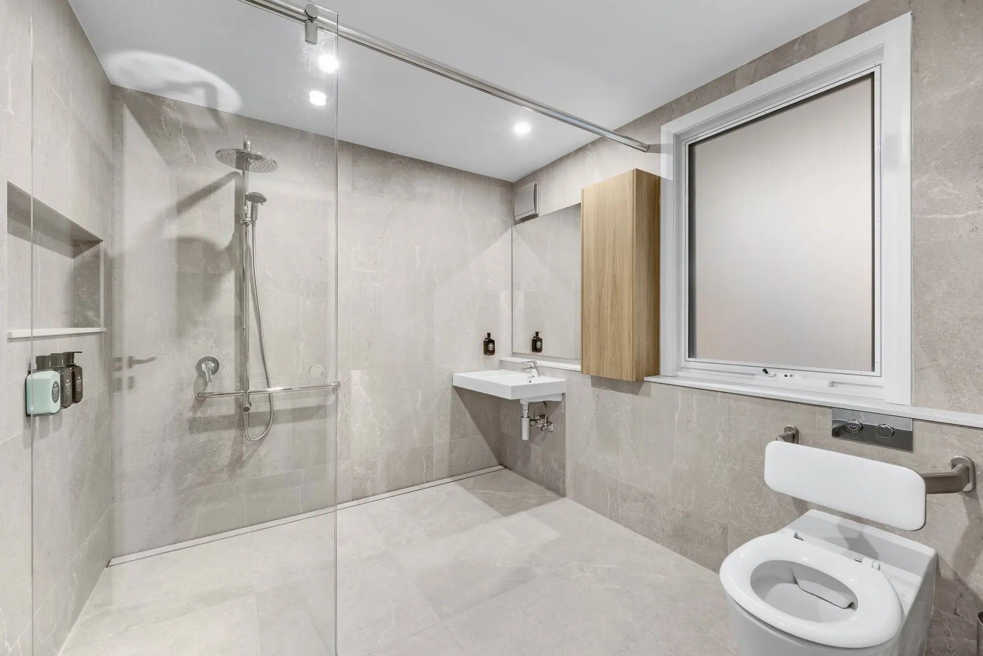 A modern bathroom with a shower, toilet, and sink.