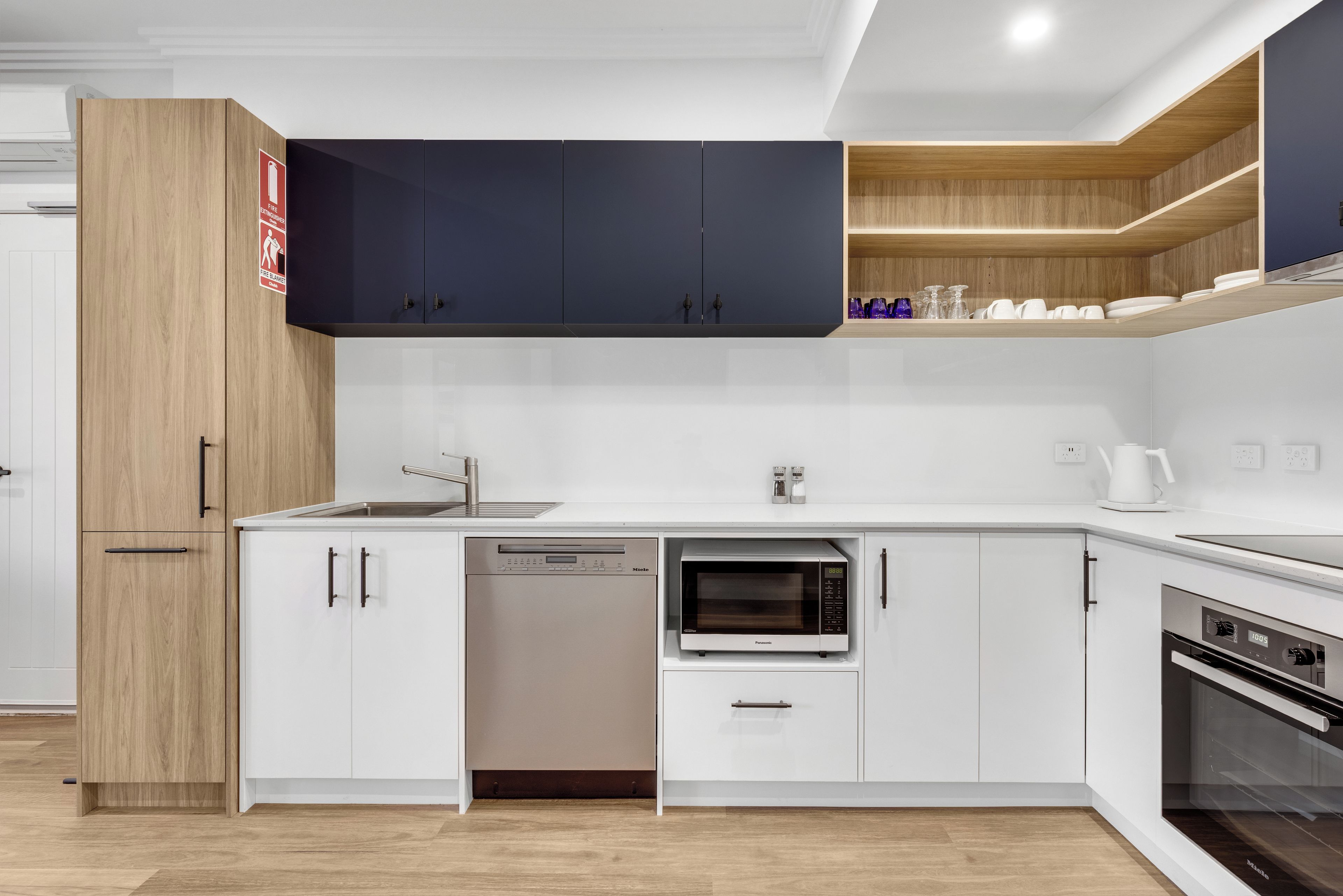 A modern kitchen with white cabinets, a dishwasher, a microwave, and an oven.