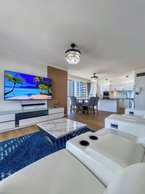 Uma sala de estar moderna com uma TV de tela plana, uma mesa de centro de mármore e um tapete azul grande.