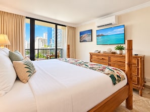 A hotel room with a large bed, a wooden dresser, a flat-screen TV, and a balcony with a city view. - Waikiki Tropical Retreat  Walk to Beach + Lanai (Honolulu)