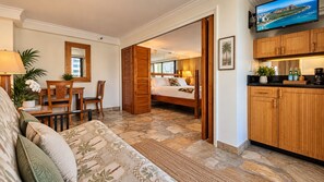 A hotel room with a bed, a desk, a chair, a sofa, and a kitchen area. - Waikiki Tropical Retreat  Walk to Beach + Lanai (Honolulu)