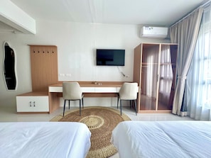 Camera d'albergo con un letto, una scrivania, due sedie, una TV, un armadio e un condizionatore d'aria.
