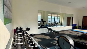Un gimnasio con equipo de ejercicio, un espejo grande y una ventana con persianas.