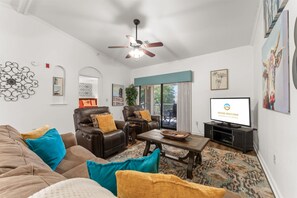 A living room with a sofa, two armchairs, a coffee table, a television, and a ceiling fan. - Foothills Getaway 2BR Home (Branson)