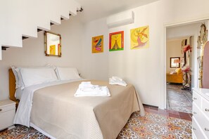 Habitació d'hotel amb llit, una taula de nit, un mirall i obra d'art a la paret.