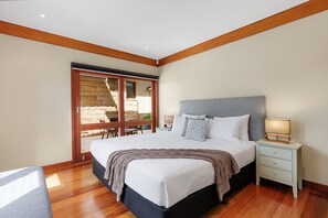 A bedroom with a large bed, a nightstand, and a sliding glass door leading to an outdoor area. - STONEWOOD - The Vintage Holiday Houses (POKOLBIN)