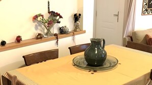 Ein Essbereich mit Holztisch, Stühlen, einer Blumenvase, einer Wanddekoration und einer Treppe.
